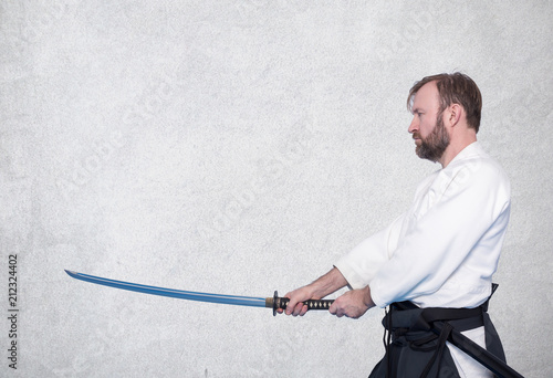 A man with katana practice Iaido against a concrete wall background photo