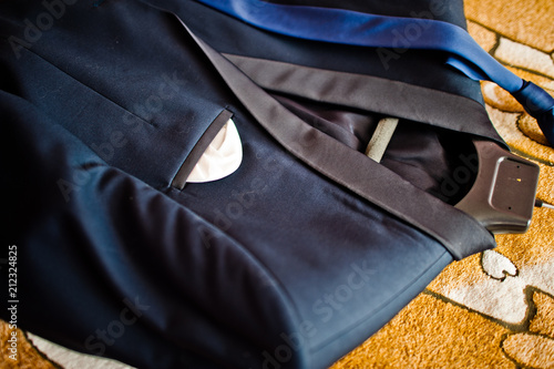 Close-up photo of a groom's suit or tuxedo on the hanger laying in the floor.
