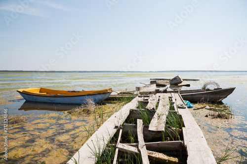 One yellow wooden boat in a lake and broken old wooden pier bridge