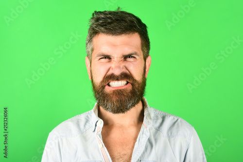Angry bearded man. Anger. Aggressive bearded man. Man with long beard and mustache. Feeling and emotions. Close Up. Emotions. Feelings. Facial expressions concept. Green background.