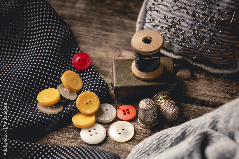 Close-up of wooden sewing spool and buttons set on wooden table - obrazy, fototapety, plakaty 