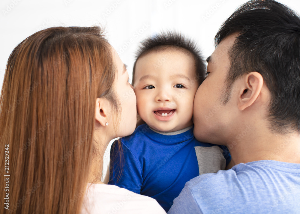 Portrait of young happy family kissing baby Portrait of young happy family kissing baby