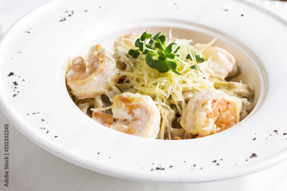 Pasta spaghetti Carbonara with cheese, king prawns and greens in white plate Pasta spaghetti Carbonara with cheese, king prawns and greens in white plate