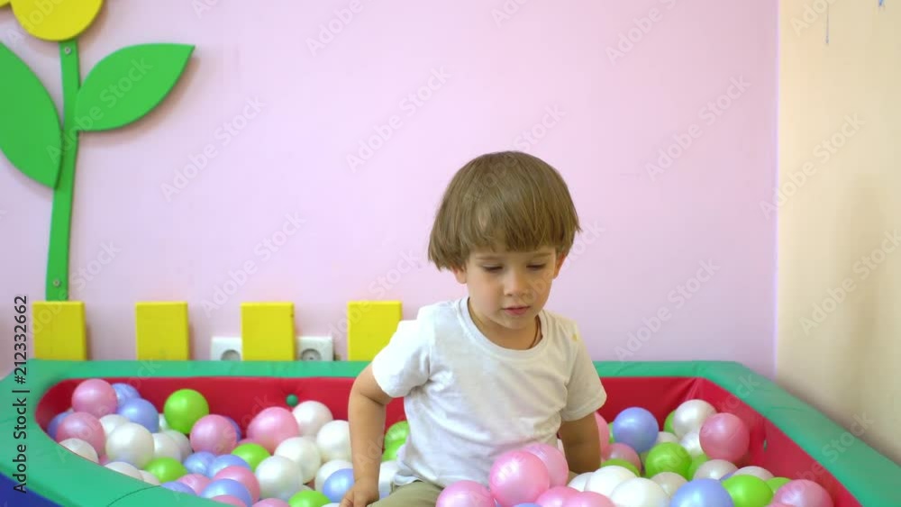 Happy cute little boy toddler smiling and playing in multi coloured ball pool. Preschool Happy cute little boy toddler smiling and playing in multi coloured ball pool. Preschool