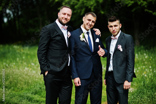 Groomsmen and groom posing outdoors on the wedding day.