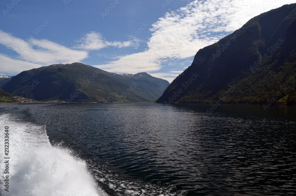 Obraz premium Mountains and fjord in Norway. Clouds and blue sky. Beautiful stunning views of mountains, water, sky, clouds and sun. Norwegian nature. Sognefjord 