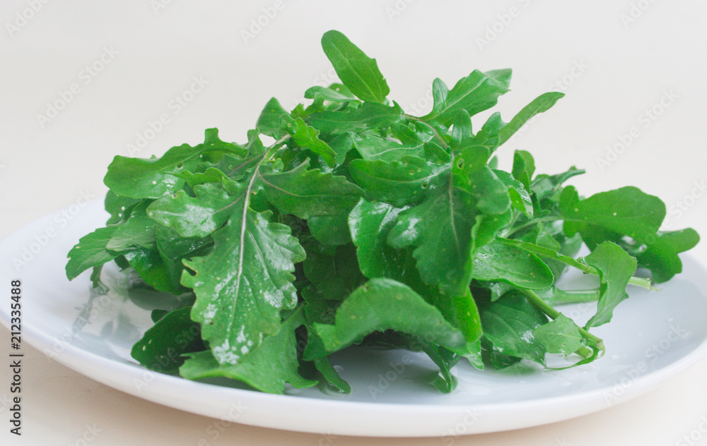 Annual rucola, leaves in a white plate. Candid. Annual rucola, leaves in a white plate. Candid.