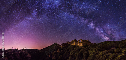 Night landscape with colorful Milky Way and yellow light at mountains.