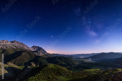 Night landscape with colorful Milky Way and yellow light at mountains.