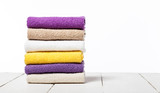 Stack of bath towels on light wooden table and white background