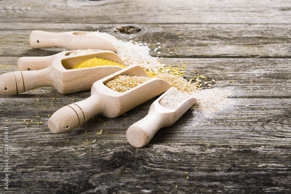 raw cereal foods: millet, brown and white rice, flour, oatmeal grains on old wood background raw cereal foods: millet, brown and white rice, flour, oatmeal grains on old wood background