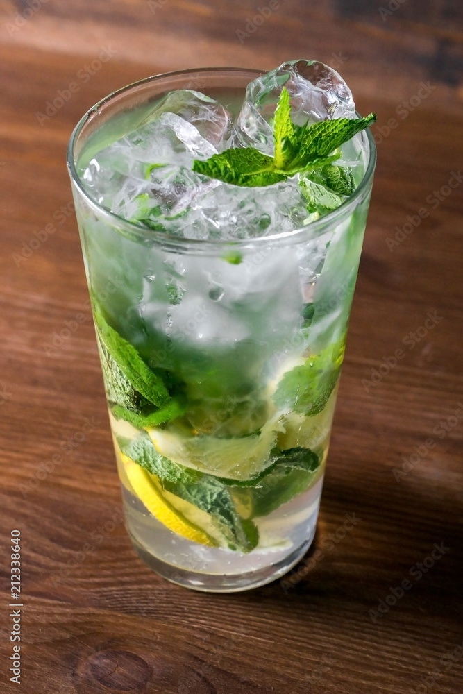 Classical mojito with lemon, soda, mint in glass on wooden background Classical mojito with lemon, soda, mint in glass on wooden background