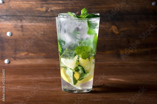 Classical mojito with lemon, soda, mint in glass on wooden background