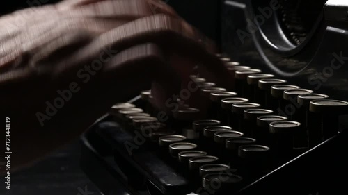 Close up shot of man typing on old vintage retro typewriter; backlit; news, media or communication concept