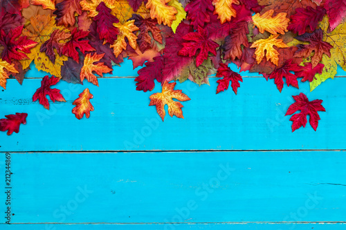 Blank antique rustic teal blue background with colorful autumn leaves border; wooden fall sign with copy space