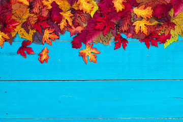 Blank antique rustic teal blue background with colorful autumn leaves border; wooden fall sign with copy space