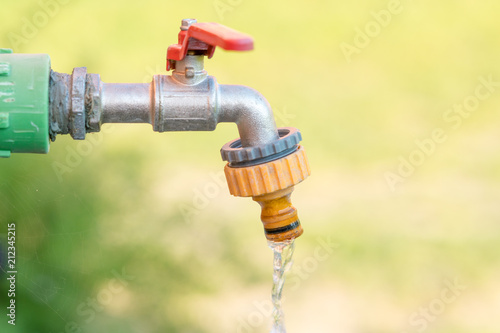 open water faucet or tap with flowing water in blur garden background