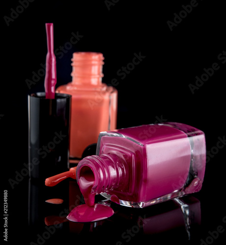 Nail polish colors spilling out of bottle on black background