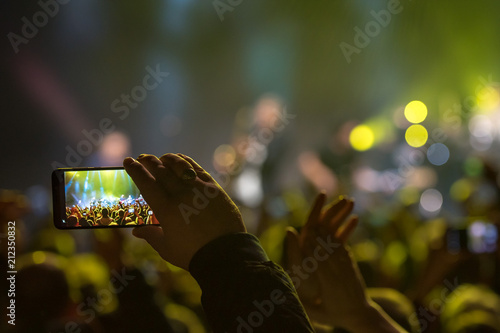 Fan holding smartphone and recording or taking picture during a concert
