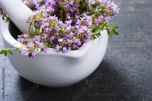 thyme flowers in a mortar on dark wood table