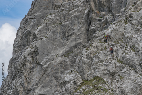 Two unrecognizable climbers facing the majestic south face of Zuc della Guardia, a mountaina in the Carnian Alps photo