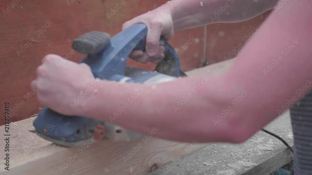 Man-Builder, working on a workbench with power tools. Construction of objects made of wood. Processing of wooden boards with a tool Man-Builder, working on a workbench with power tools. Construction of objects made of wood. Processing of wooden boards with a tool