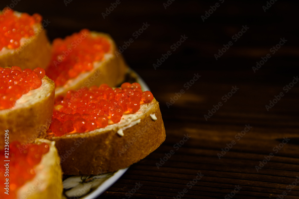 Sandwiches with red caviar on wooden table