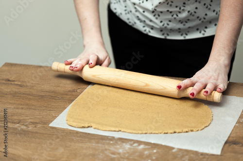Hands rolling dough for gingerbread on the wooden table