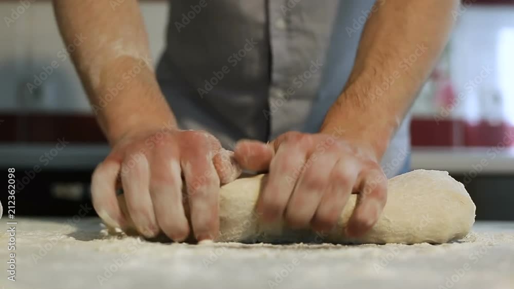 Men's hands prepare pizza dough on the table in the kitchen Men's hands prepare pizza dough on the table in the kitchen