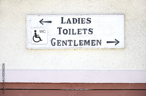 Ladies gentlemen disabled toilets wc sign on plain wall background