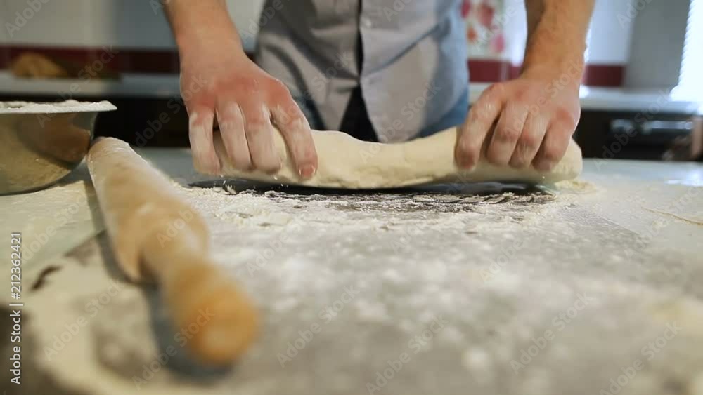 Men's hands prepare pizza dough on the table in the kitchen Men's hands prepare pizza dough on the table in the kitchen