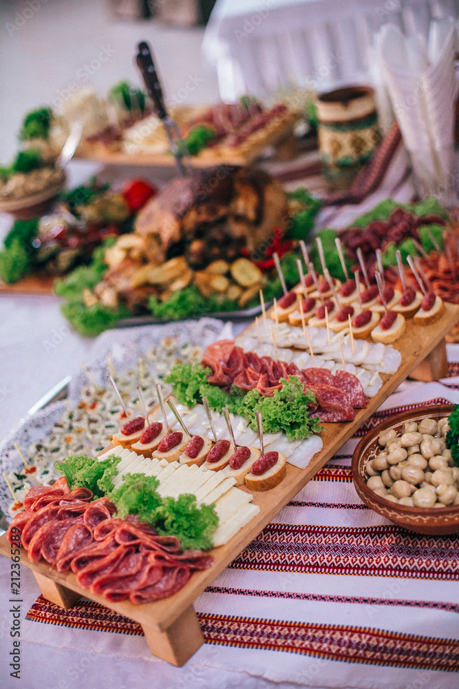 Meat assortment of sausage, smoked meat, on a wooden board on wedding table