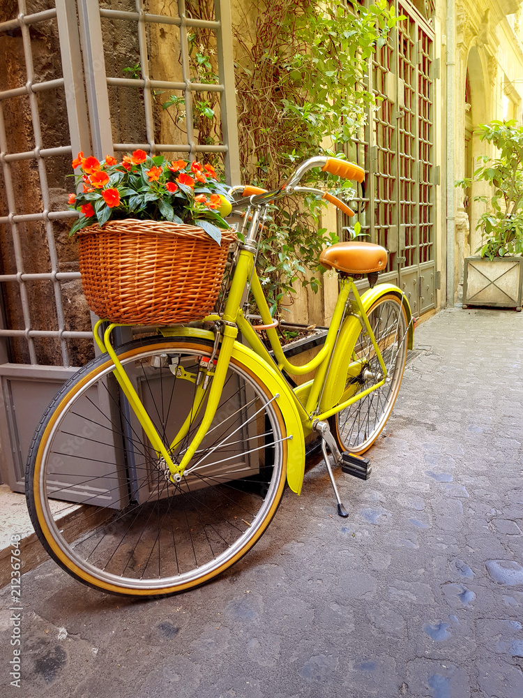 Colorful yellow bicycle parked on the old narrow street in Rome, Italy