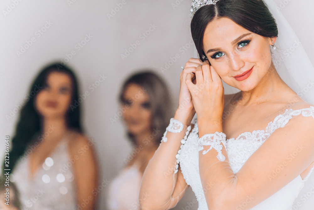 Happy bridesmaid hugging the bride in the bedroom in the morning. Before wedding ceremony. Bride preparing and wait groom.
