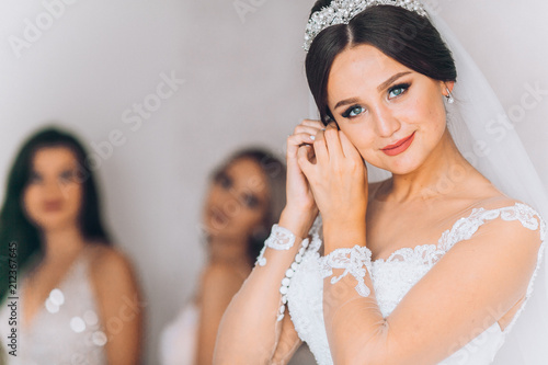 Happy bridesmaid hugging the bride in the bedroom in the morning. Before wedding ceremony. Bride preparing and wait groom.  photo