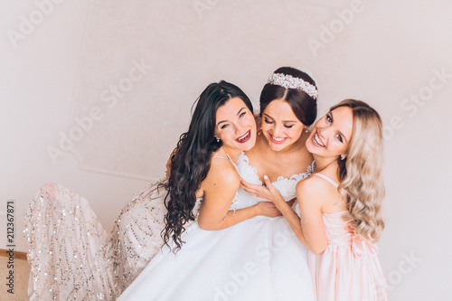 Fotografi Happy bridesmaid hugging the bride in the bedroom in the morning