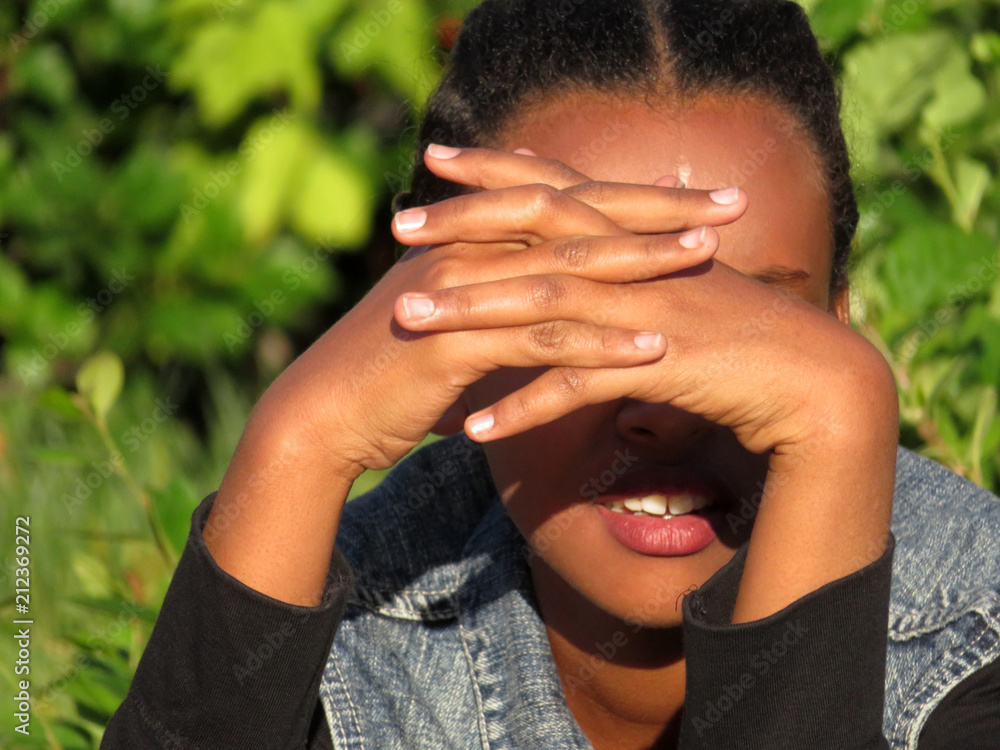 african-young-girl-with-hands-covering-her-face-from-the-sun-on-green