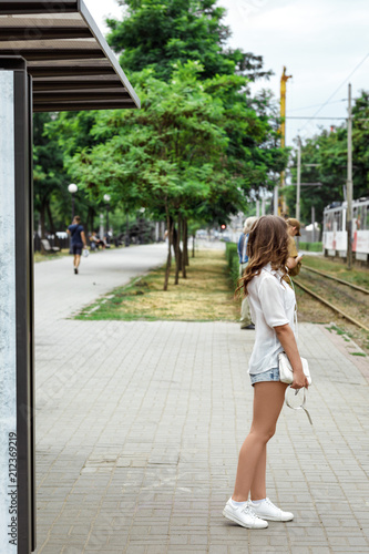 girl is standing at the bus stop