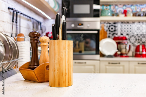 Kitchen knives in a special wooden stand with spice jars. Close-up. Kitchen concept