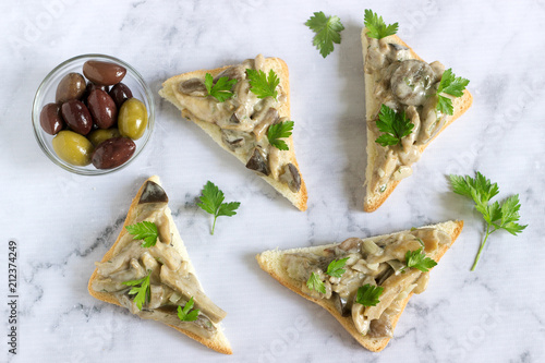 Triangular sandwiches with summer mushrooms cooked with cream and herbs served with olives.