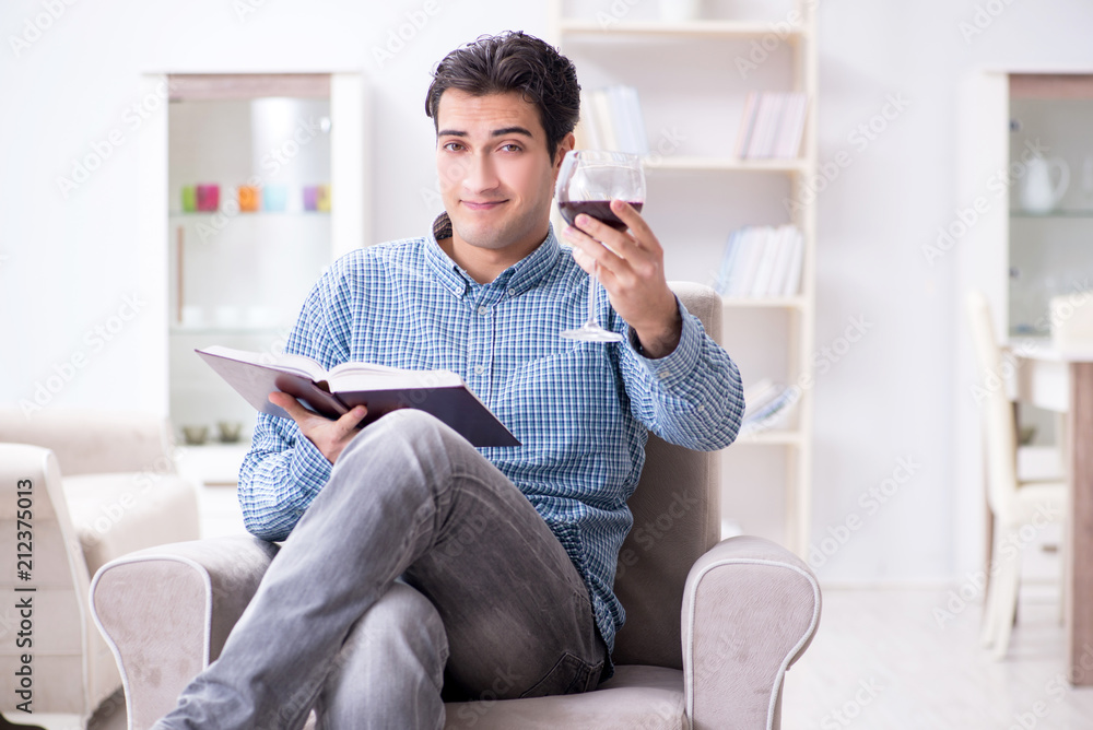 Fototapeta premium Young man drinking wine at home