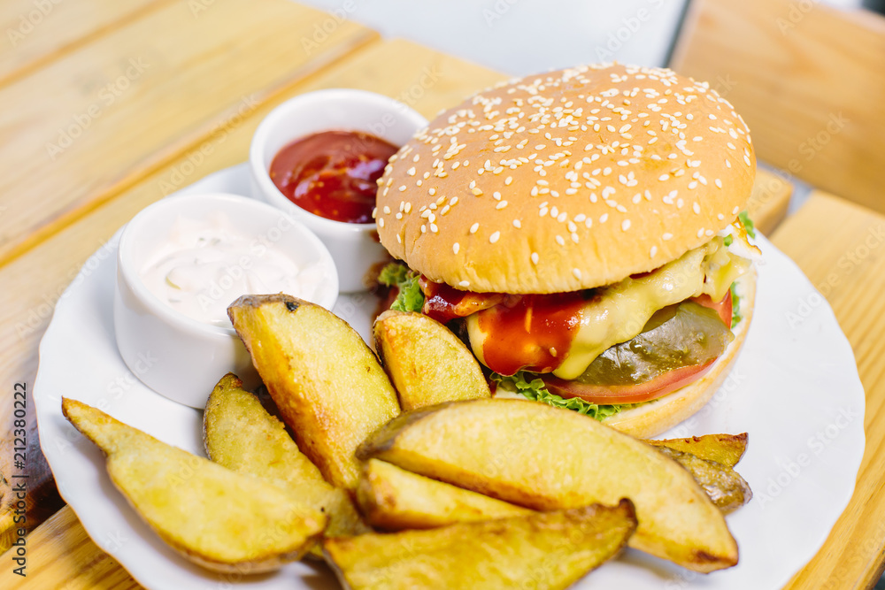 Homemade cheese burger or hamburger on wood plate served with french fries put on black granite table with copy space. Fast food for breakfast or lunch. Homemade cheese burger or hamburger on wood plate served with french fries put on black granite table with copy space. Fast food for breakfast or lunch.