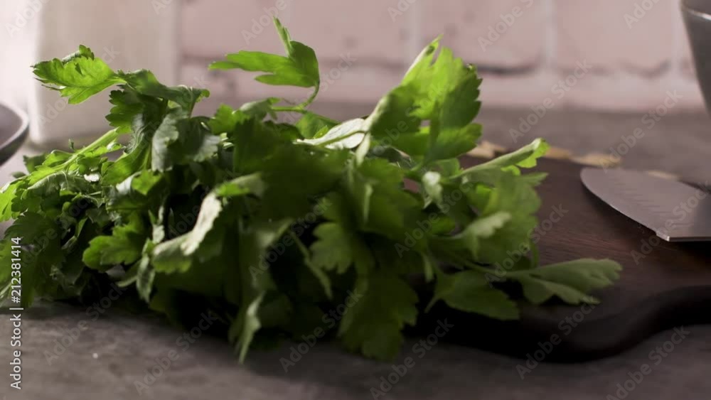 Fresh garden herbs on kitchen countertop. Parsley, garlic, knife and almons. The concept of food, healthy food.