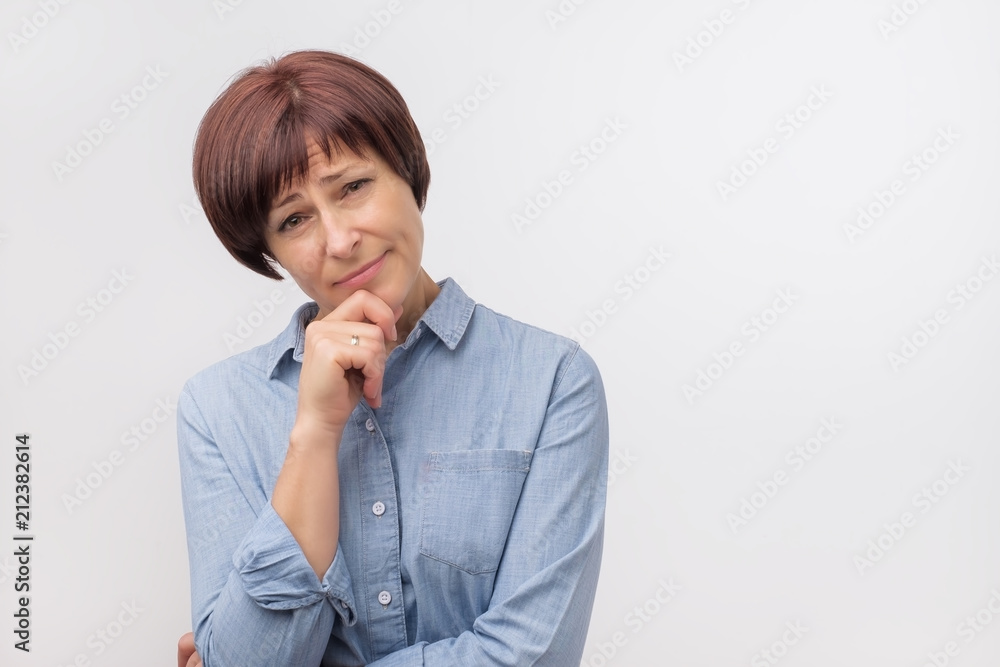 Portrait of mature confident woman in blue shirt standing on grey background Portrait of mature confident woman in blue shirt standing on grey background