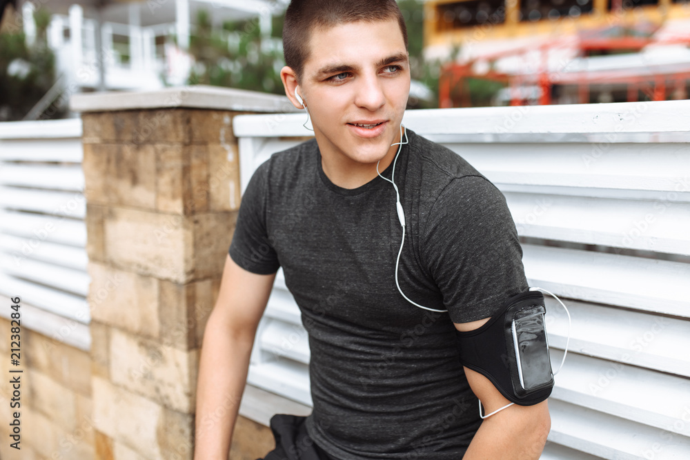 Fototapeta premium Athletic man posing on wall background, morning jog, exercise, rest after Jogging