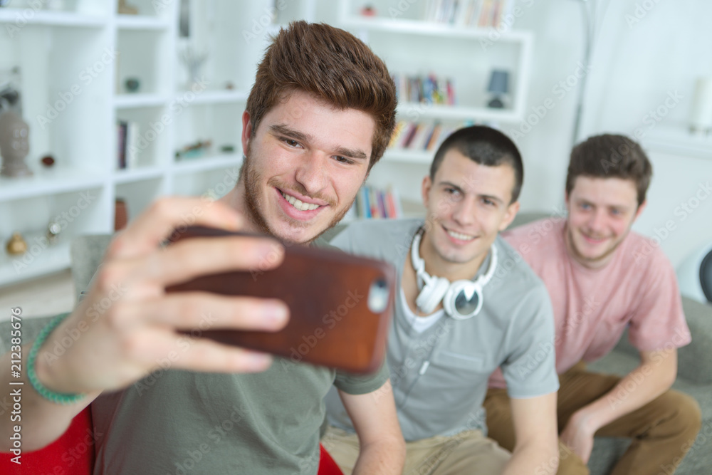 Fototapeta premium Three young men taking self portrait photograph with cellphone