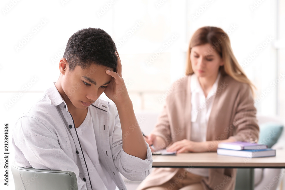 Young female psychologist working with teenage boy in office
