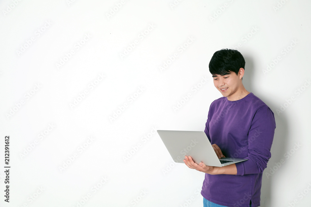 Man in casual clothes with laptop on light background