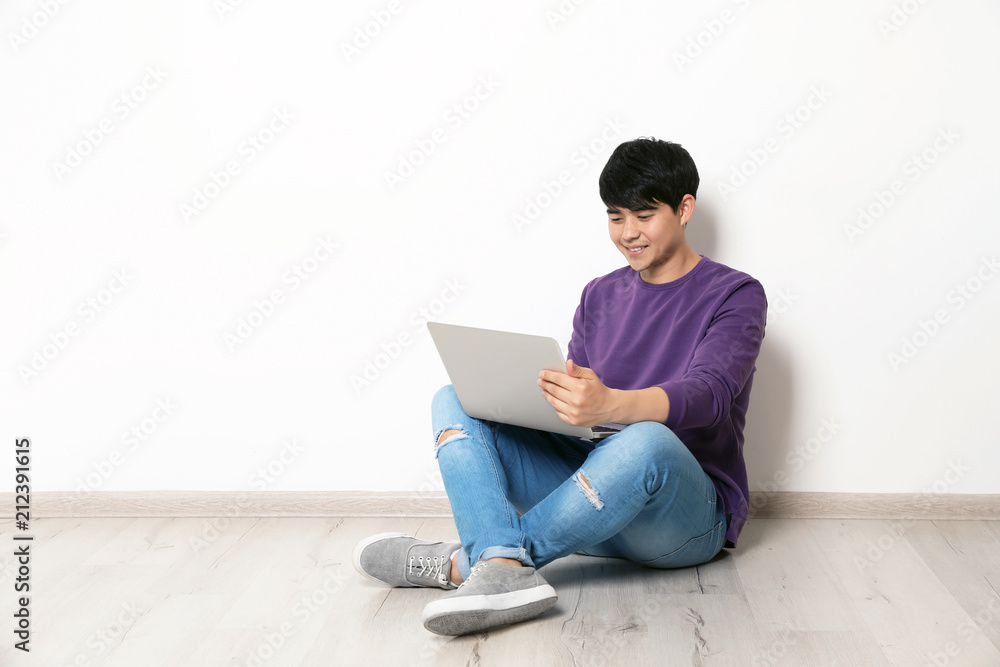 Man in casual clothes with laptop near light wall Man in casual clothes with laptop near light wall