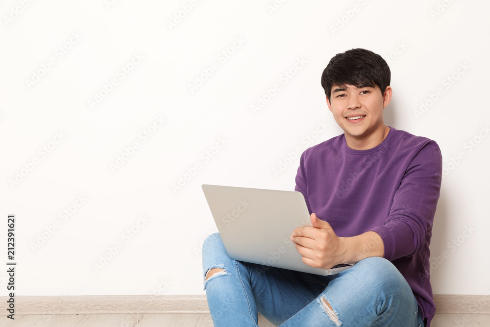 Man in casual clothes with laptop near light wall Man in casual clothes with laptop near light wall